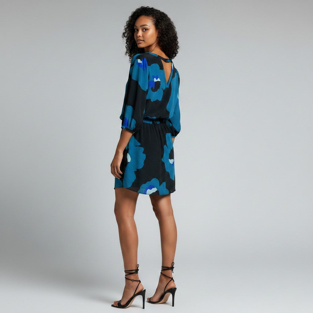 A woman wear black heels and A floral print dress on a light gray studio background.