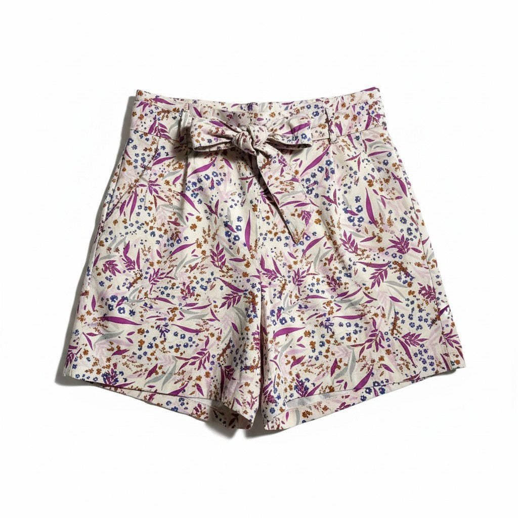 A pair of women's shorts featuring an all-over floral and botanical print on a cream base, with a matching fabric tie belt at the waist. The print contains purple, pink, blue, and brown elements.
