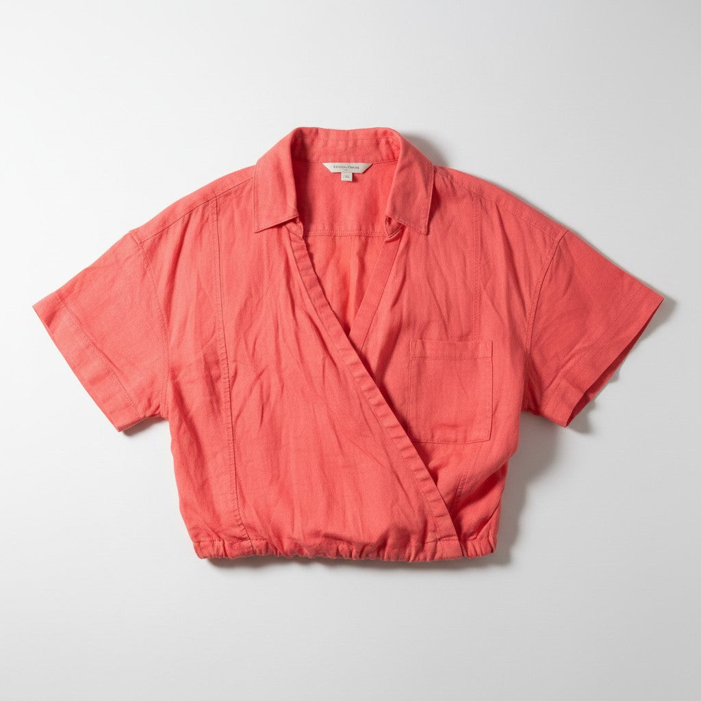 A coral pink short-sleeve linen wrap shirt with a collar and chest pocket, laid flat on a light gray background.