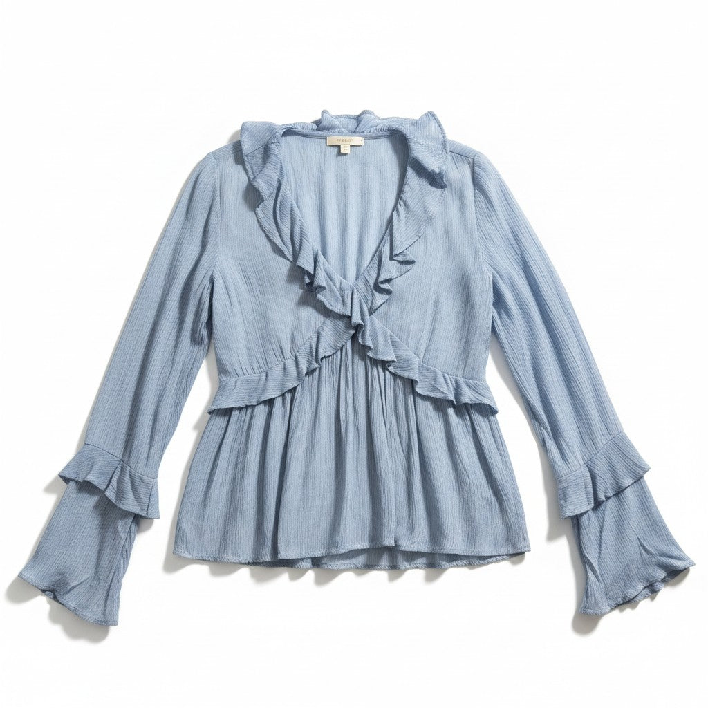 A light blue long-sleeve blouse with a ruffled wrap-style neckline, ruffled waist detail, and ruffled cuffs, laid flat on a white background.