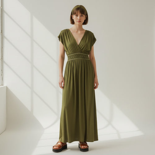 Woman wearing a green dress standing in a softly lit room.