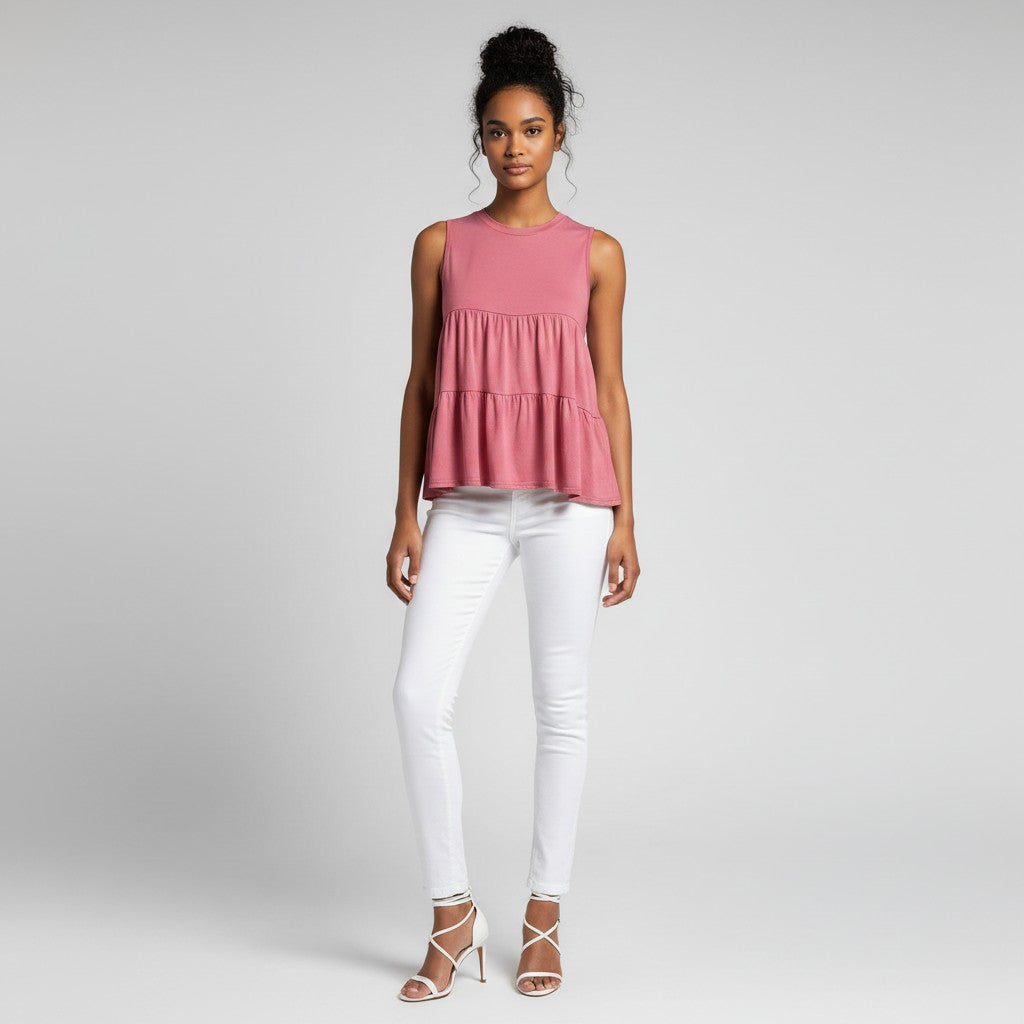 a woman wearing a pink shirt with white jeans on a light gray studio background.