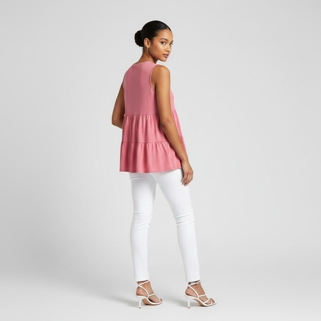 a woman wearing a pink shirt with white jeans on a light gray studio background.