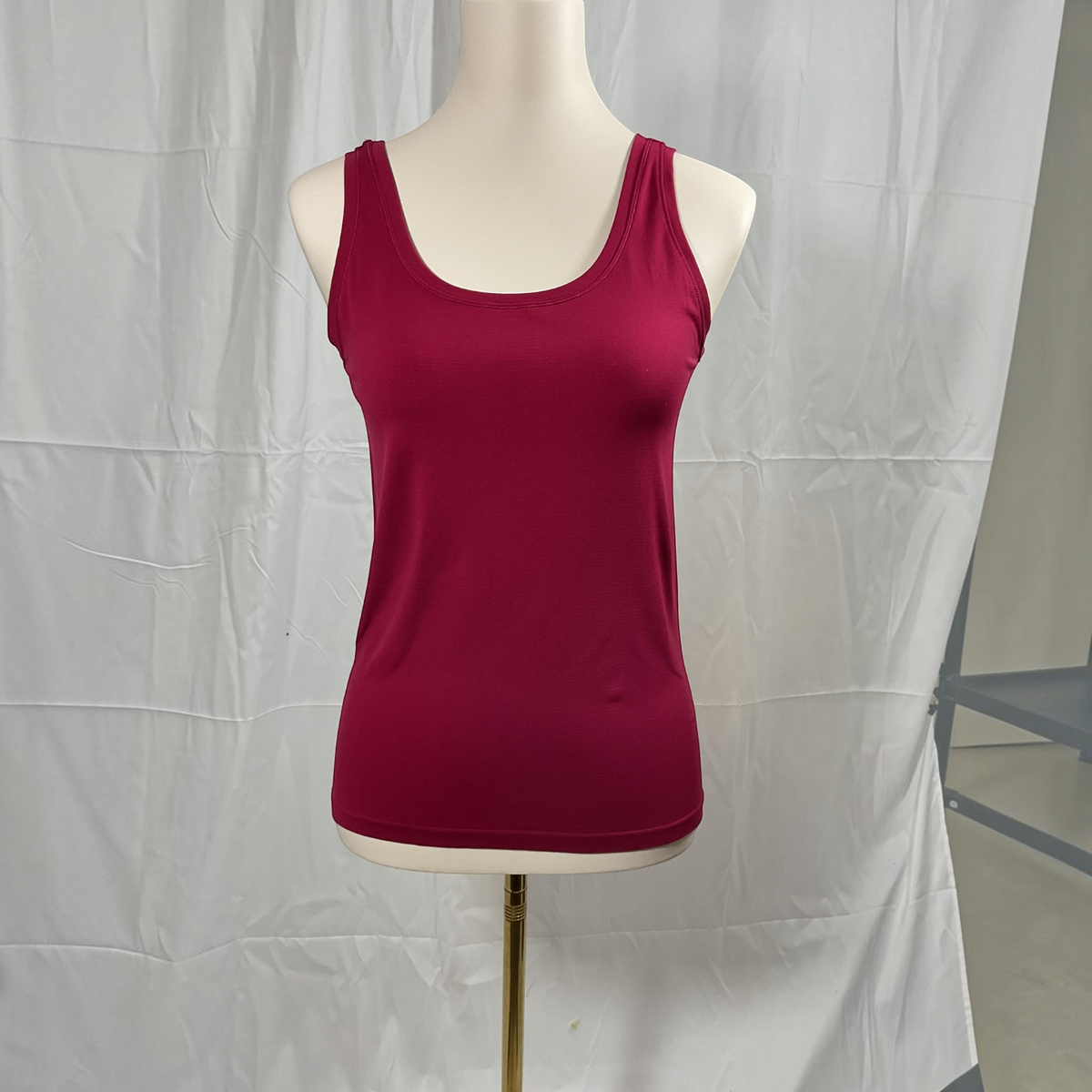 A woman wearing a red tank top with black jeans on a studio background