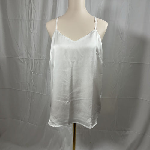Woman wearing a white tank top and blue jeans on a plain background