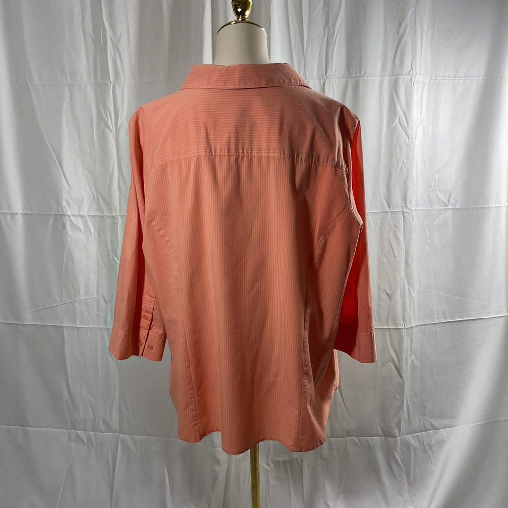 A coral pink long-sleeve button-down shirt displayed on a dress form mannequin against a wrinkled white backdrop.