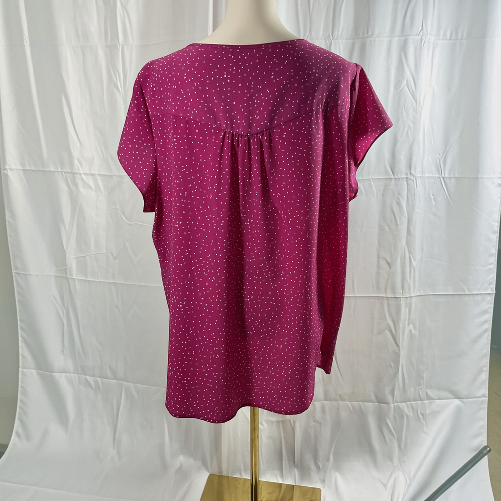 A short-sleeve top displayed on a mannequin torso against a white fabric backdrop. The top is a deep magenta pink with a small white polka dot pattern and a gathered back neckline.
