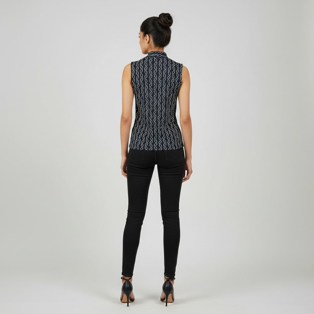 A woman viewed from behind wearing a sleeveless black vest with a white geometric pattern, paired with black skinny jeans and black high heels, against a light gray studio background.