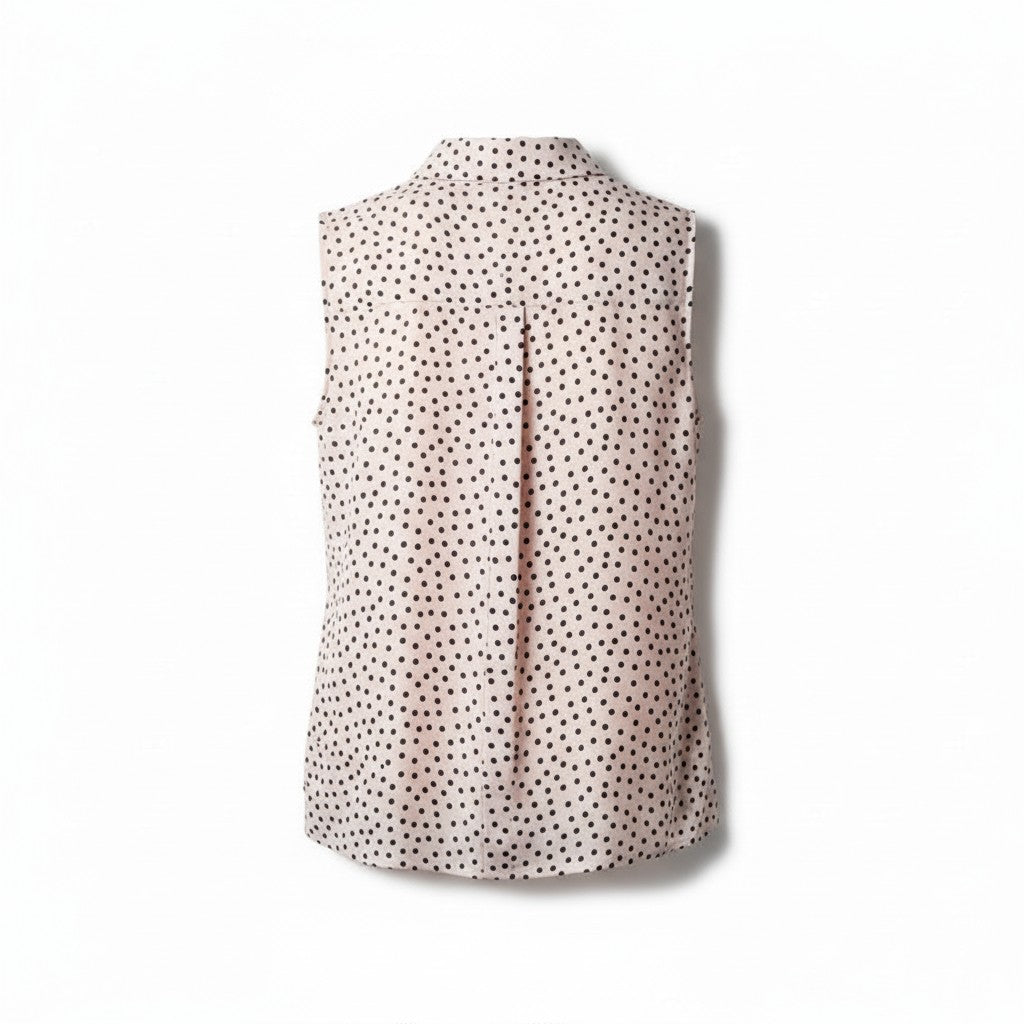 A sleeveless collared blouse with a dense black polka dot pattern on a light pinkish-beige background, shown from the back against a white studio background.