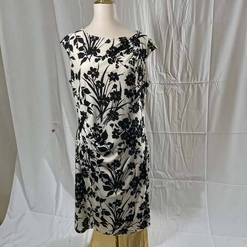A sleeveless black and white floral print dress displayed on a mannequin torso against a wrinkled white fabric backdrop.