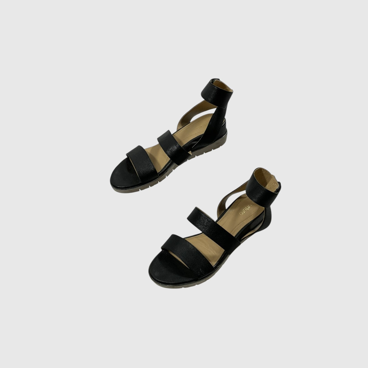 A pair of black leather strappy sandals with ankle straps, displayed on a light gray background.