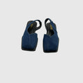 A pair of dark blue suede slingback flats with square toes and black soles, shown from a top-down view on a light gray background.