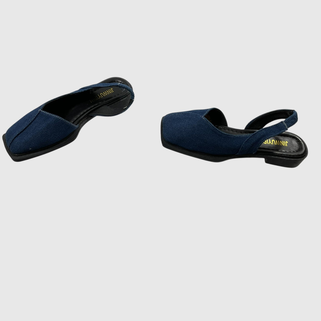 A pair of navy blue velvet clogs with black soles and straps, displayed from different angles on a light gray background. The brand name 'SUKHDEV' is printed in gold on the insole.