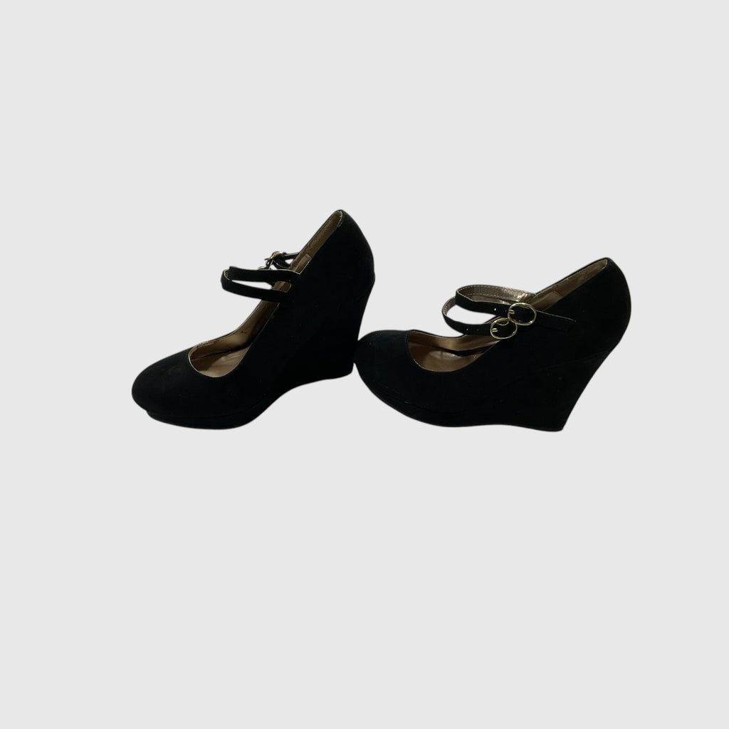 A pair of black suede Mary Jane pumps with gold-tone buckle straps, shown from a side view on a light gray background.
