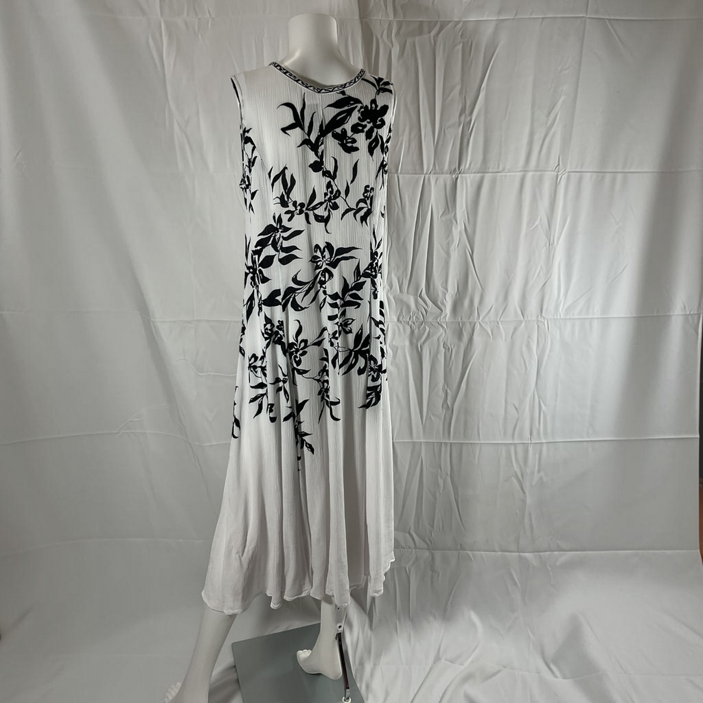 A sleeveless white dress with a black floral vine pattern and a beaded neckline, displayed on a mannequin against a wrinkled white fabric backdrop.