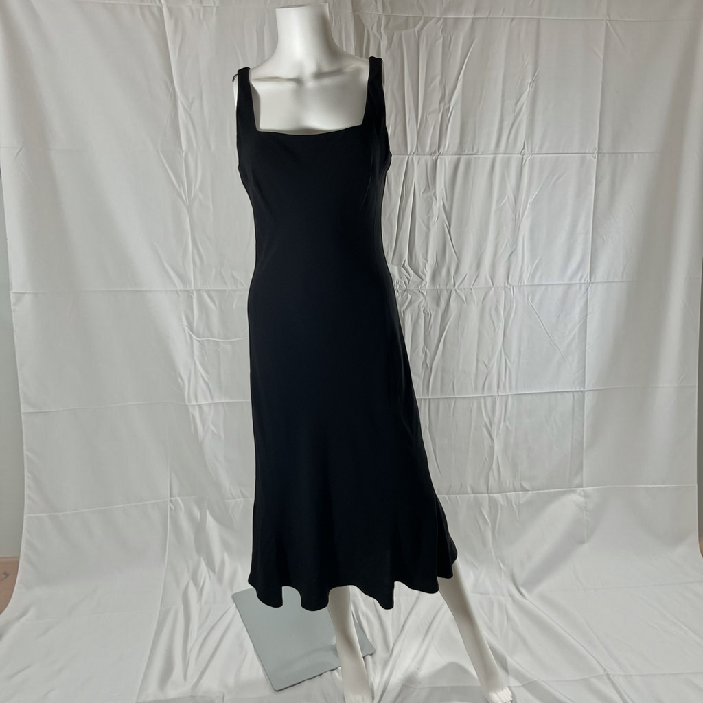 A black sleeveless midi dress with a square neckline and wide shoulder straps, displayed on a white mannequin against a wrinkled white fabric backdrop.