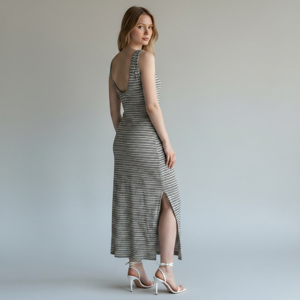 A woman modeling a sleeveless, one-shoulder midi dress with a gray and white horizontal stripe pattern, shown from a three-quarters back view against a neutral studio backdrop.