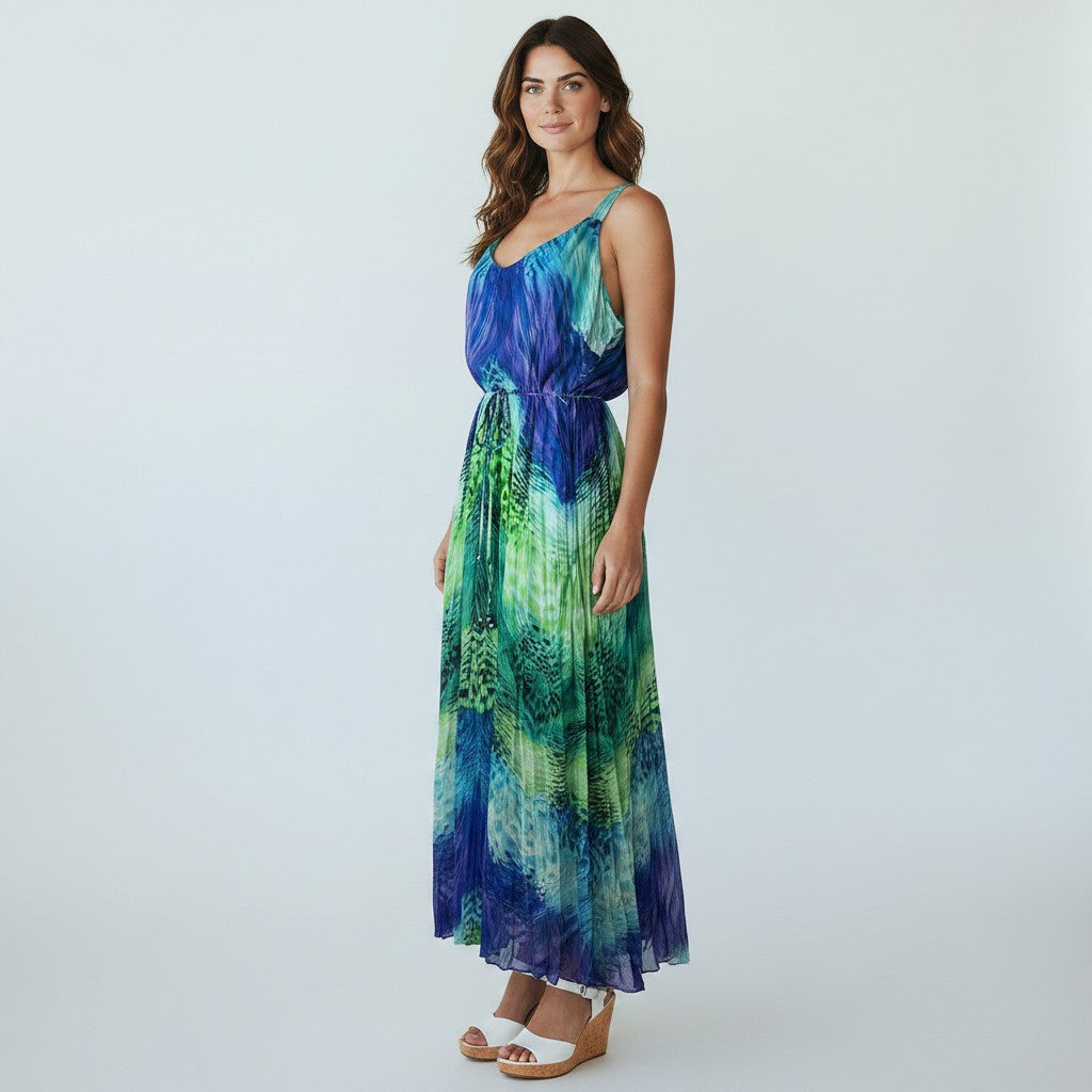 A woman modeling a sleeveless maxi dress with a blue and green abstract print, standing against a light gray studio background.