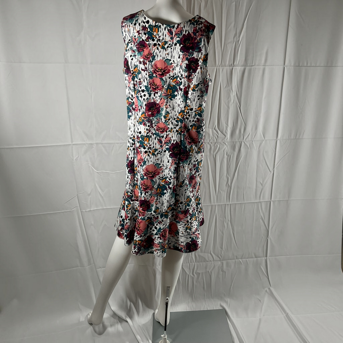 A sleeveless fit-and-flare dress with a vibrant floral print, displayed on a white mannequin against a wrinkled white studio backdrop.