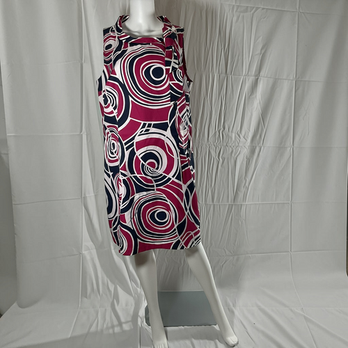 A sleeveless collared dress displayed on a white mannequin against a wrinkled white backdrop. The dress features a bold abstract spiral pattern in magenta, navy blue, and white.