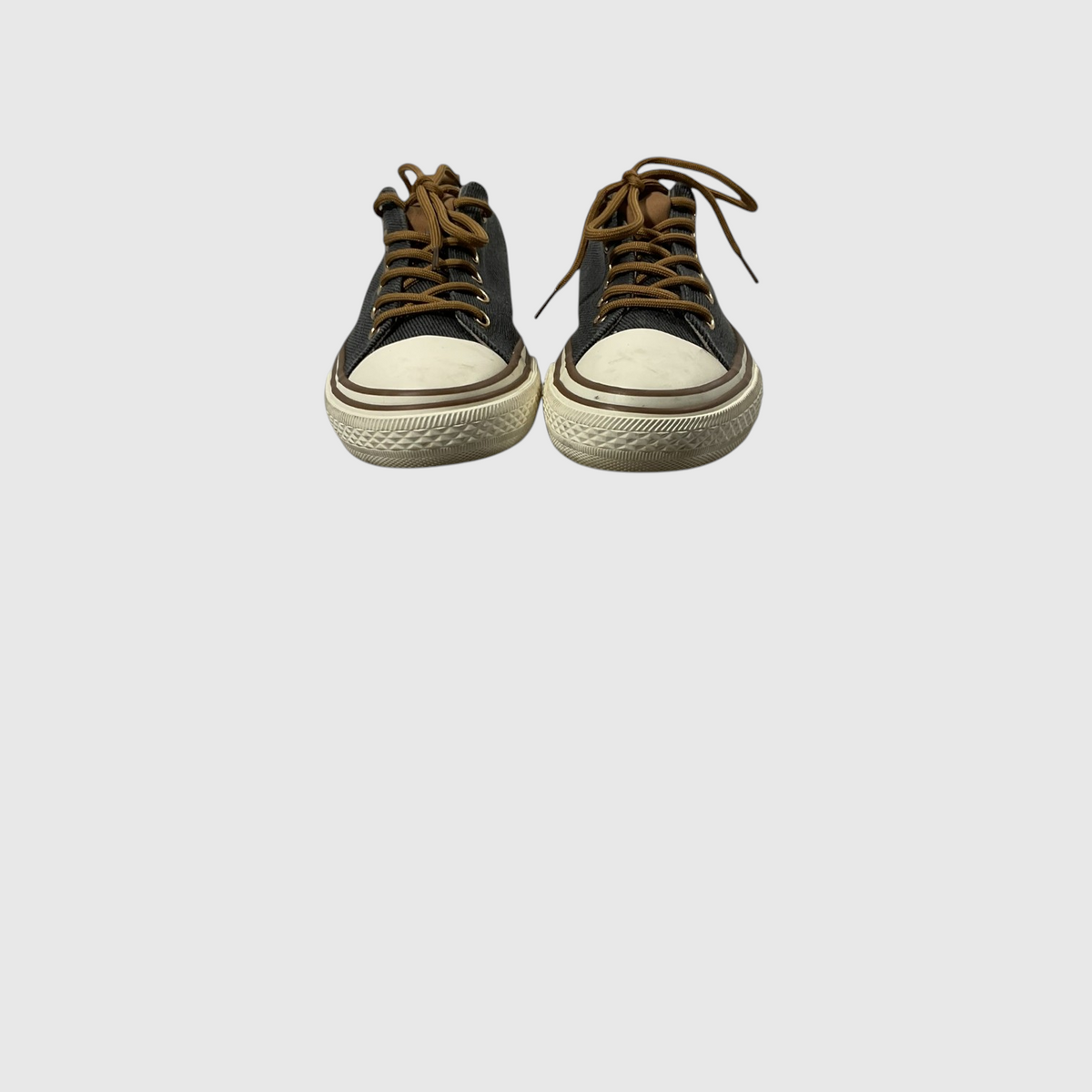 Pair of gray sneakers with white laces on a light gray background