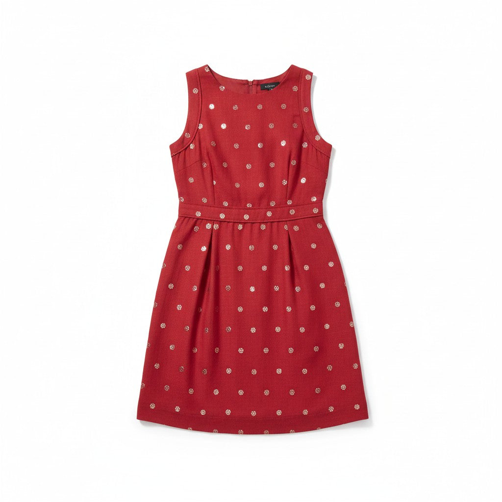 A woman modeling a sleeveless red A-line dress with a white polka-dot pattern, paired with black ankle-strap heels, against a neutral light gray studio background.