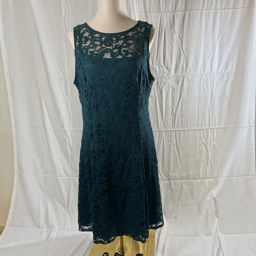 A sleeveless dark teal lace dress displayed on a mannequin torso against a wrinkled white fabric backdrop.