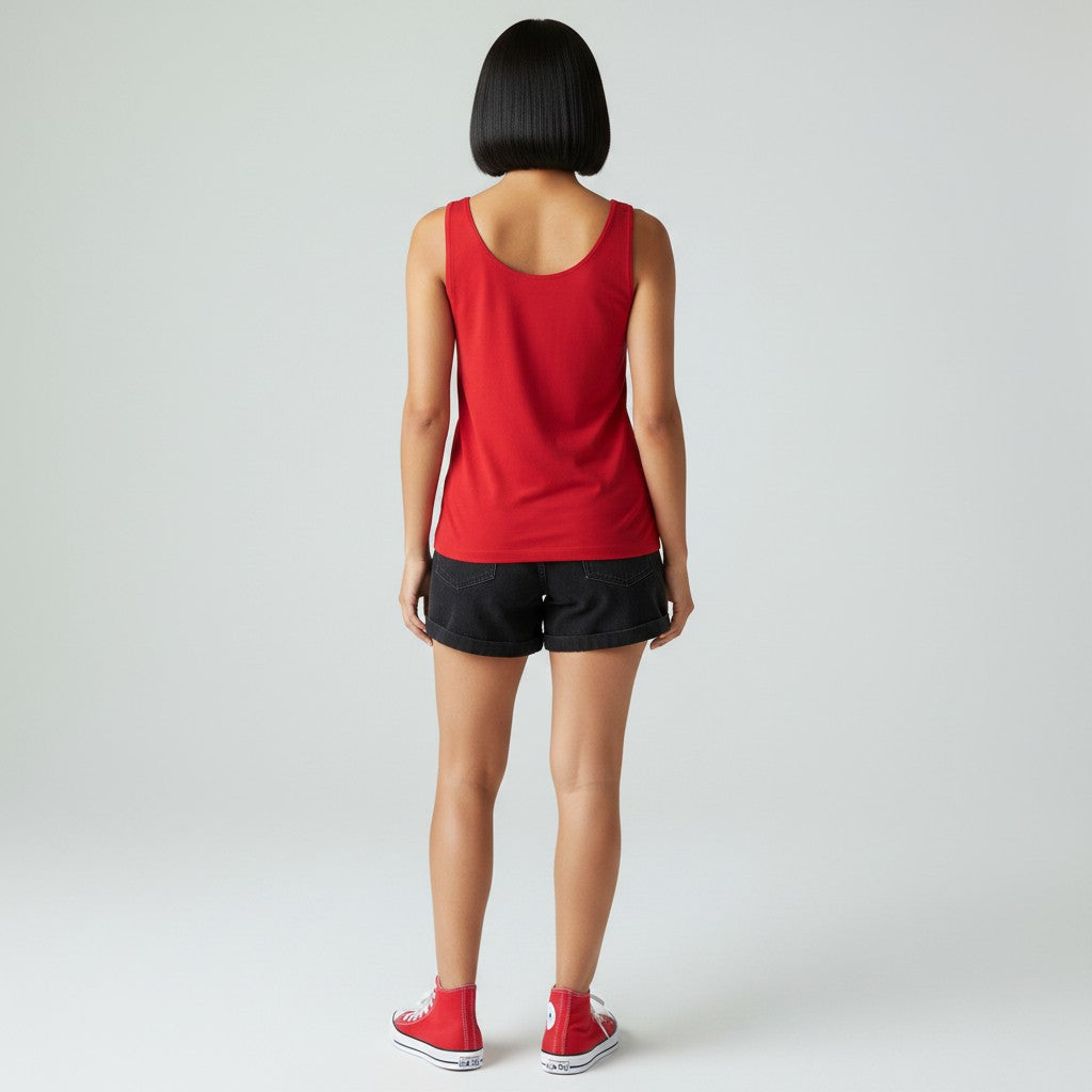 A woman viewed from behind wearing a bright red sleeveless tank top, black athletic shorts, and red sneakers against a light gray studio background.