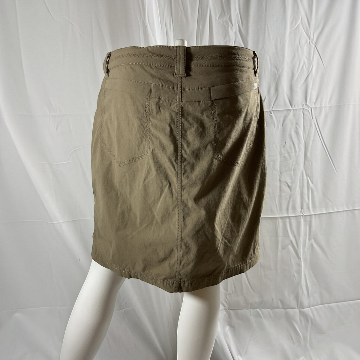 A beige mini skirt with belt loops, and back pockets, laid flat on a light gray background