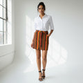 A woman wearing a white shirt with a strip skirt and black heels on a gray background
