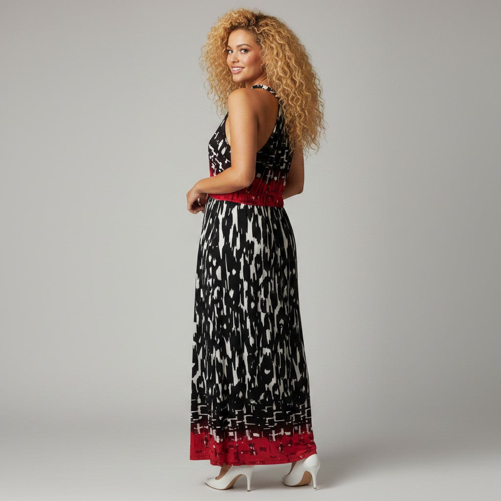 A woman modeling a sleeveless halter-neck maxi dress with a black and white ikat pattern and red trim, photographed against a neutral gray studio background.