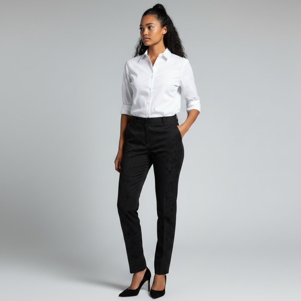 A woman modeling a white long-sleeve button-down shirt and black trousers, paired with black high heels, against a light gray studio background.