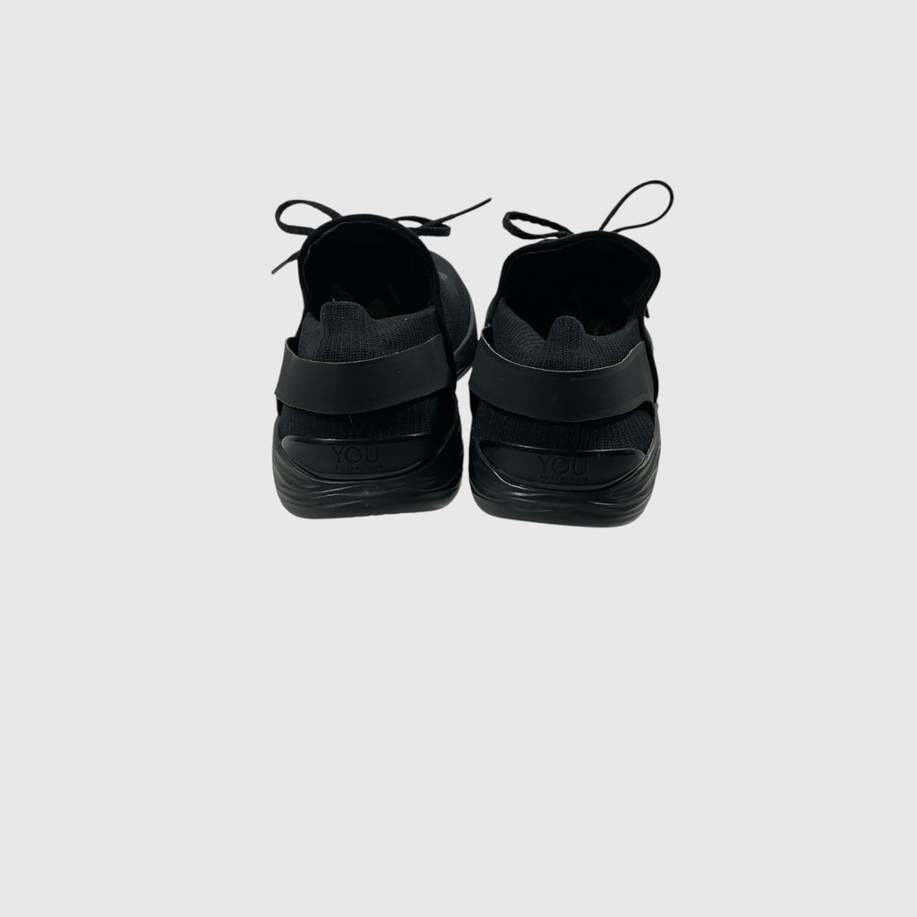 A pair of black slip-on sneakers shown from the back against a light gray background.