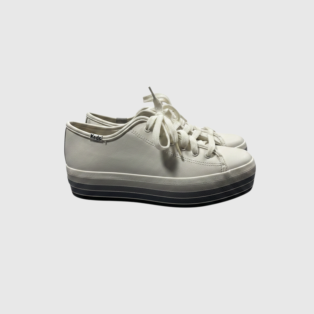 A pair of low-top platform sneakers in off-white canvas with white laces and a thick black and gray striped platform sole, shown against a light gray background.