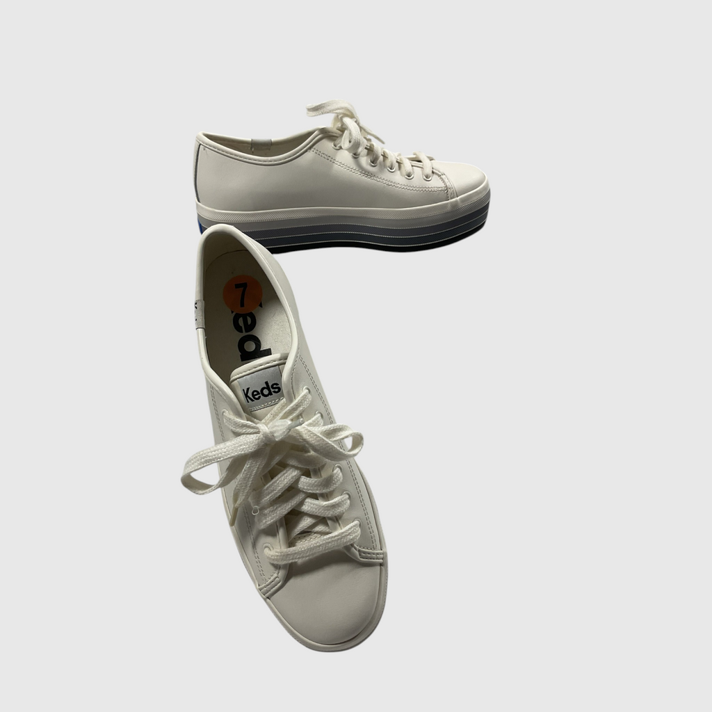 A pair of Keds low-top platform sneakers in off-white leather, featuring white laces and a stacked sole with a black and white design, shown on a light gray background.