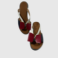 A pair of women's flat sandals with a color-blocked design featuring burgundy, navy blue, and off-white straps, set against a light gray background.