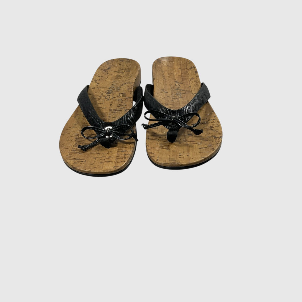 A pair of black thong sandals with textured straps and cork-look soles, shown on a light gray background.