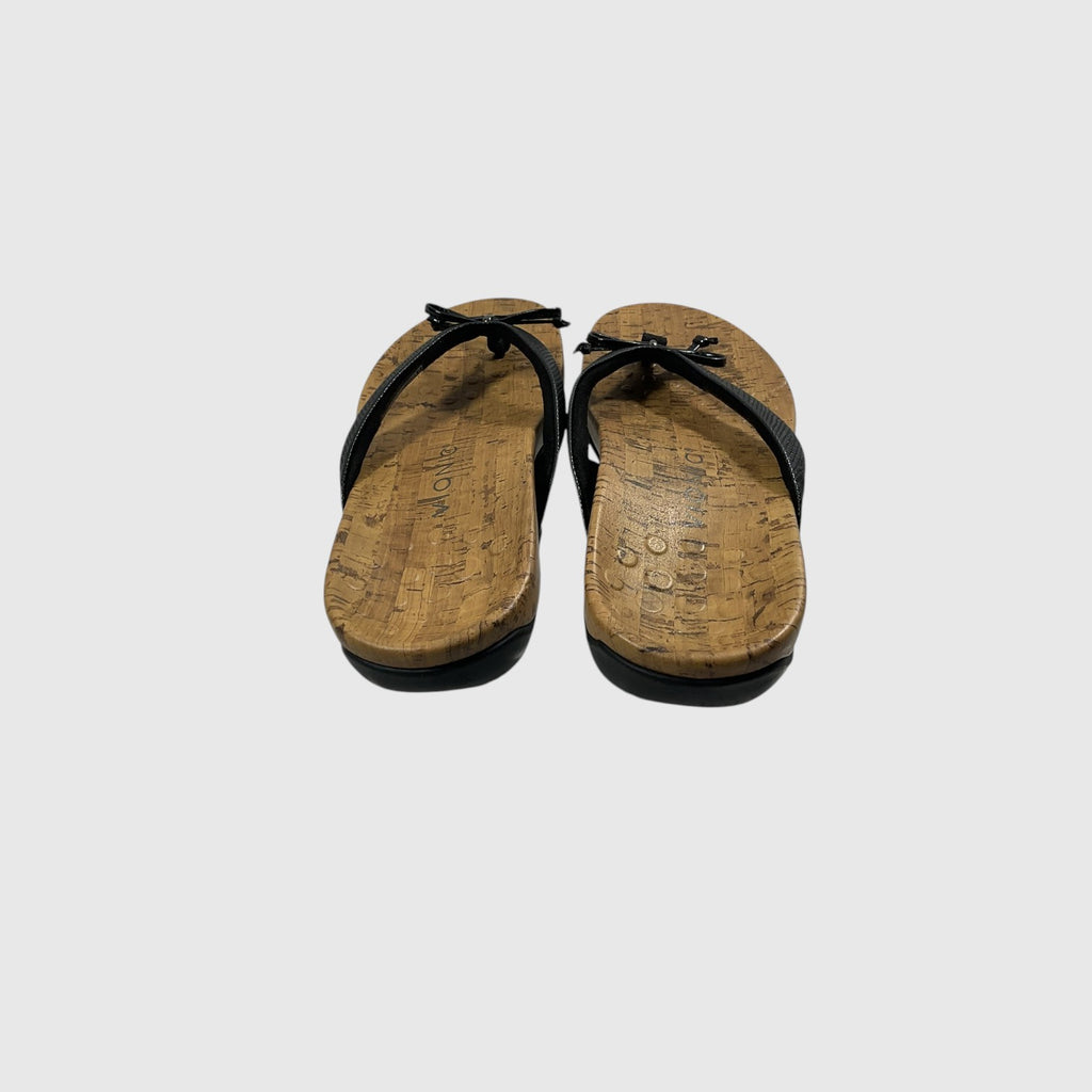 A pair of black thong sandals with textured straps and cork-look soles, shown on a light gray background.