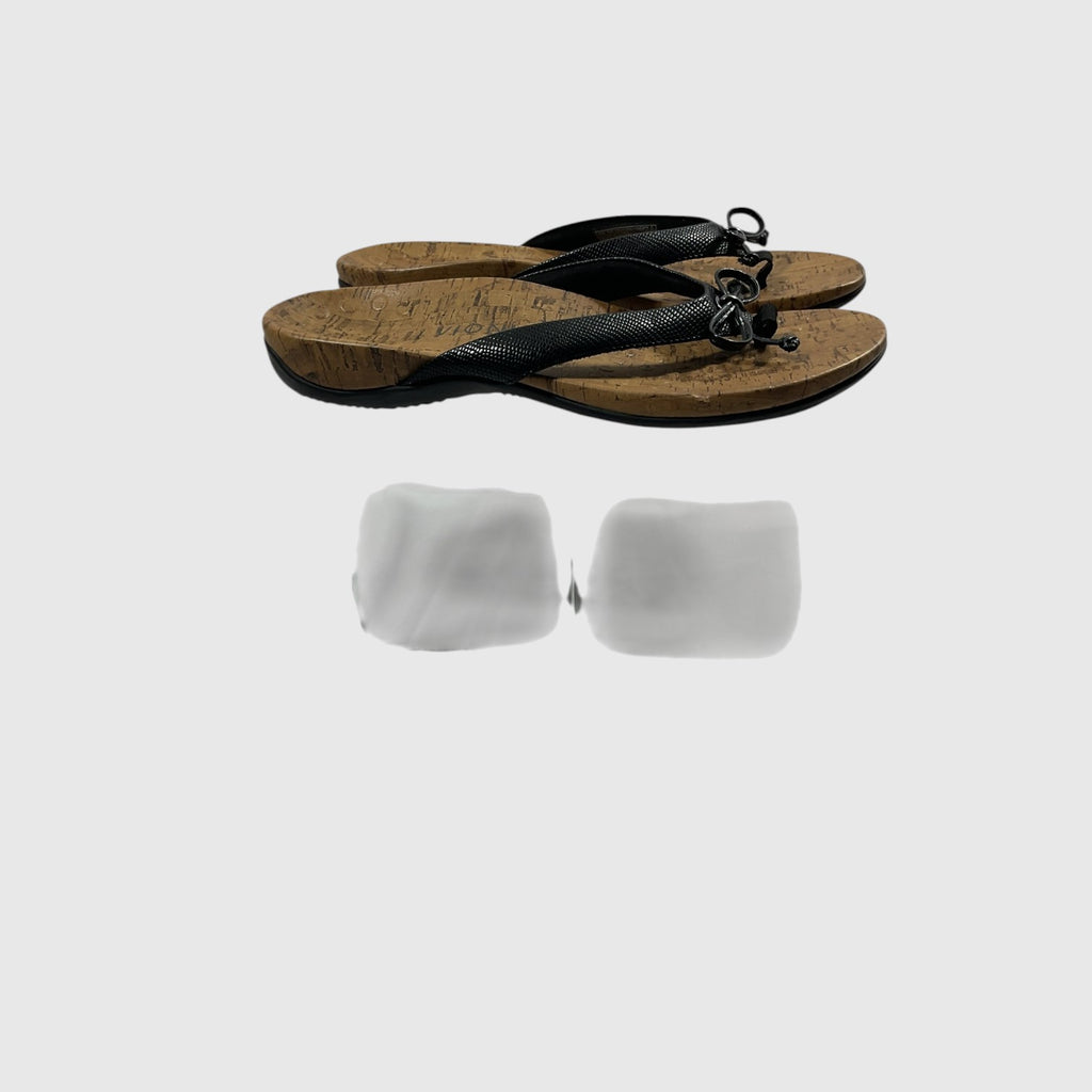 A pair of black thong sandals with textured straps and cork-look soles, shown on a light gray background.