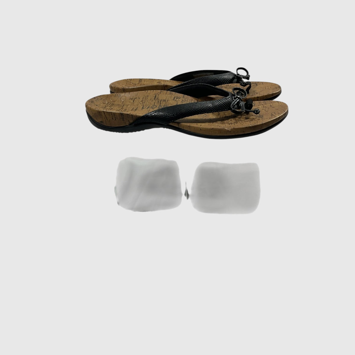 A pair of black thong sandals with textured straps and cork-look soles, shown on a light gray background.