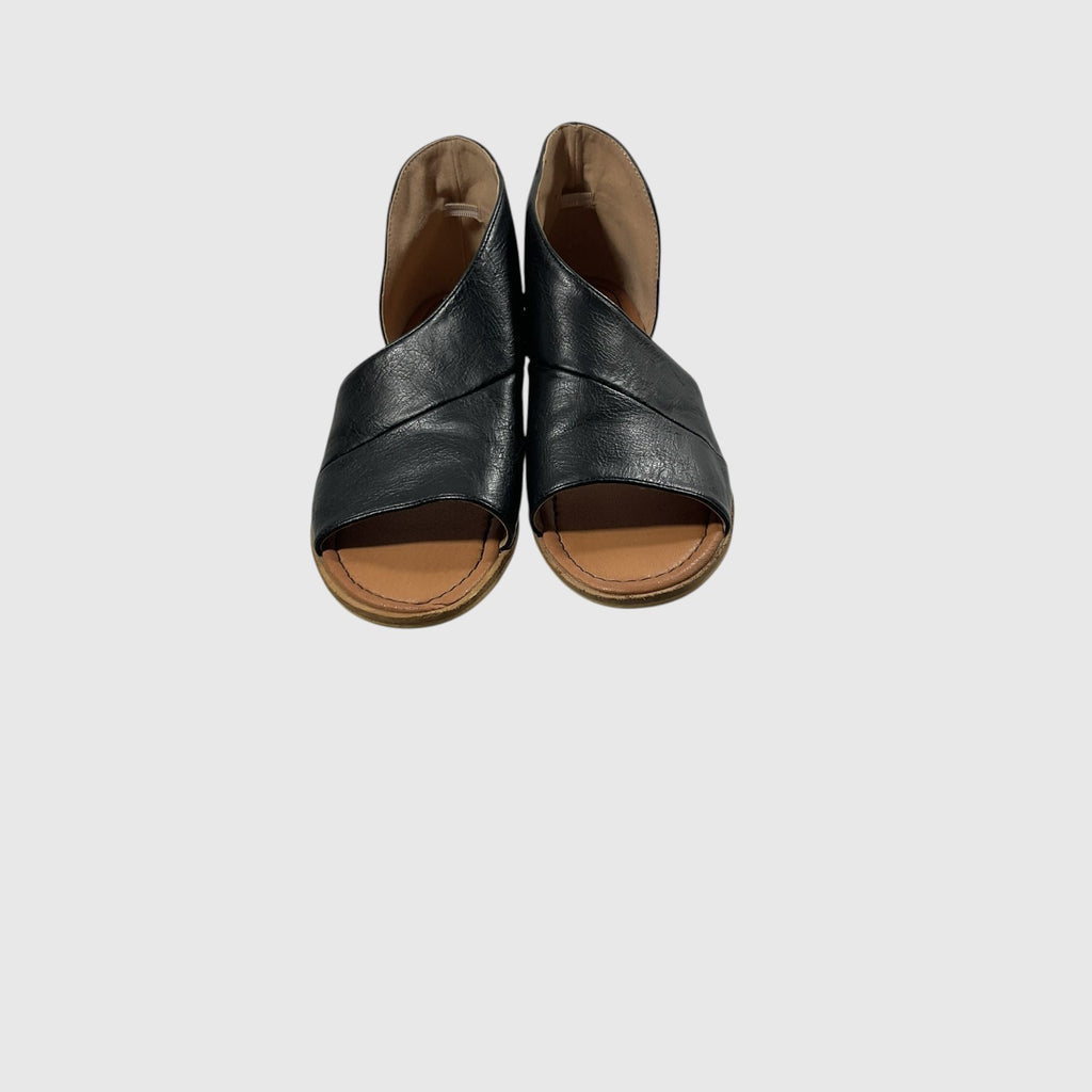 A pair of women's open-toe slide sandals with crisscrossing black leather straps and tan footbeds, shown from a top-down view on a light gray background.