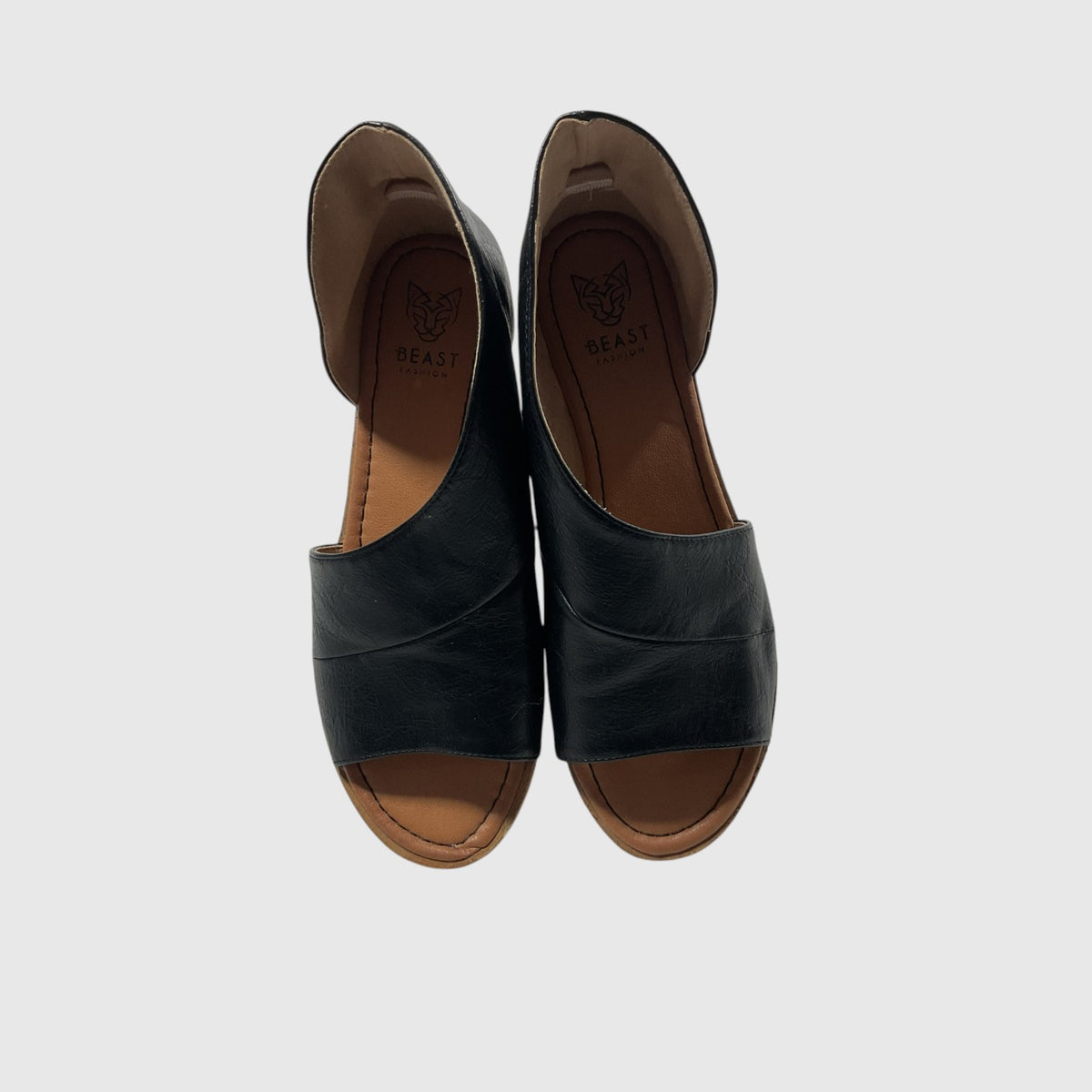 A pair of black leather peep-toe slide sandals with brown insoles, shown from a top-down view on a light gray background. The brand name 'BEAST' is visible on the insole.