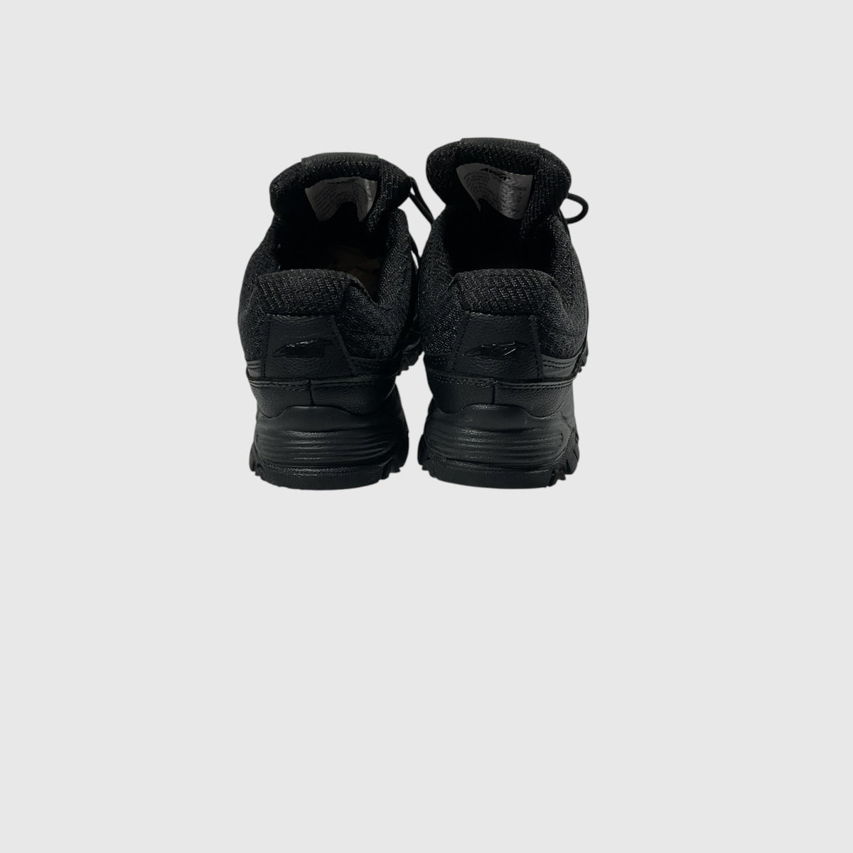 A pair of black low-top lace-up shoe with a textured synthetic and mesh upper, black laces, and a rugged black sole, shown from a side profile on a light gray background.