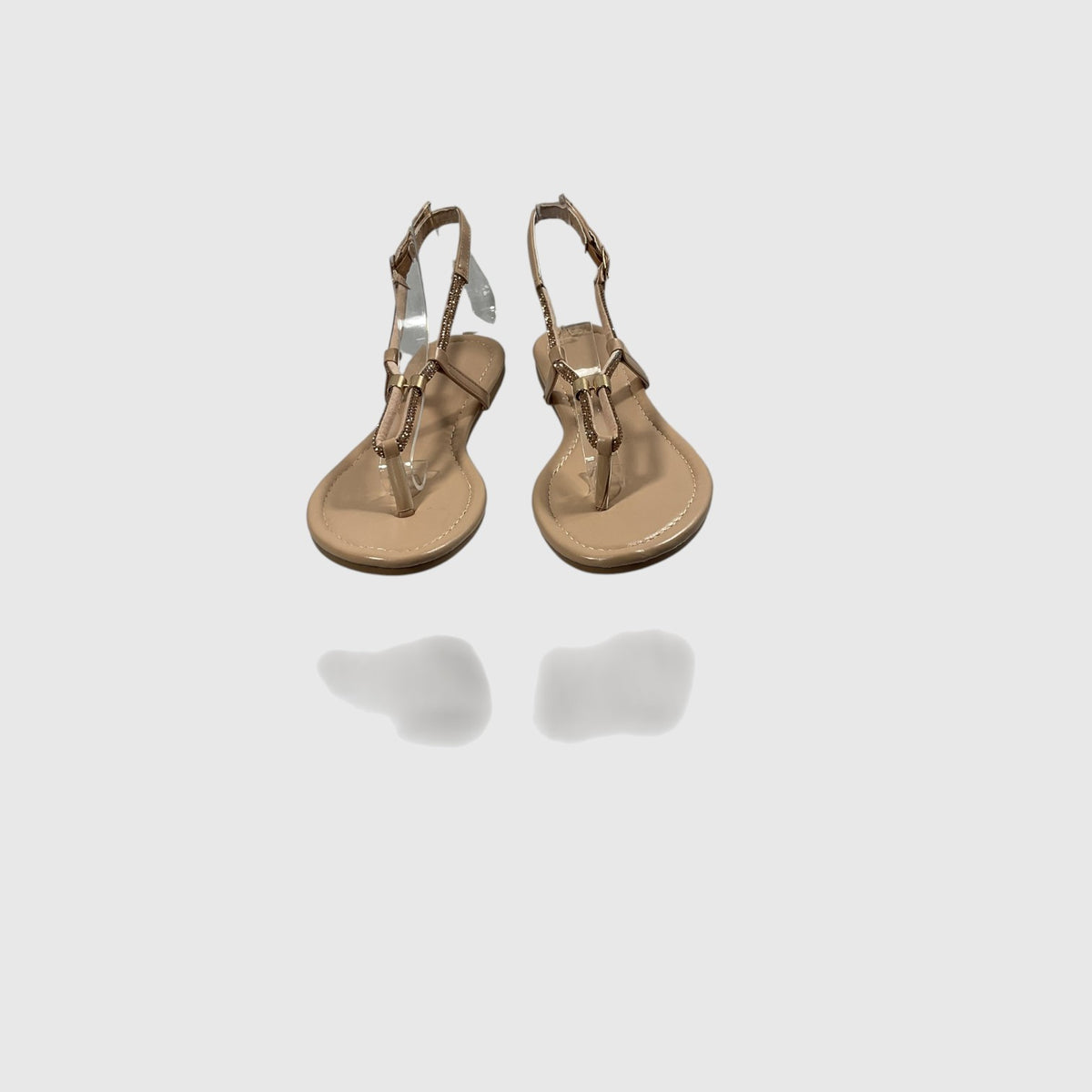 A pair of metallic gold T-strap sandals with adjustable ankle straps, displayed on a light gray reflective surface.