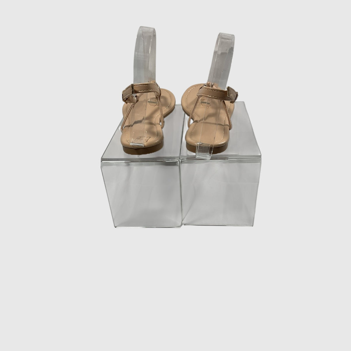 A pair of metallic gold T-strap sandals with adjustable ankle straps, displayed on a light gray reflective surface.