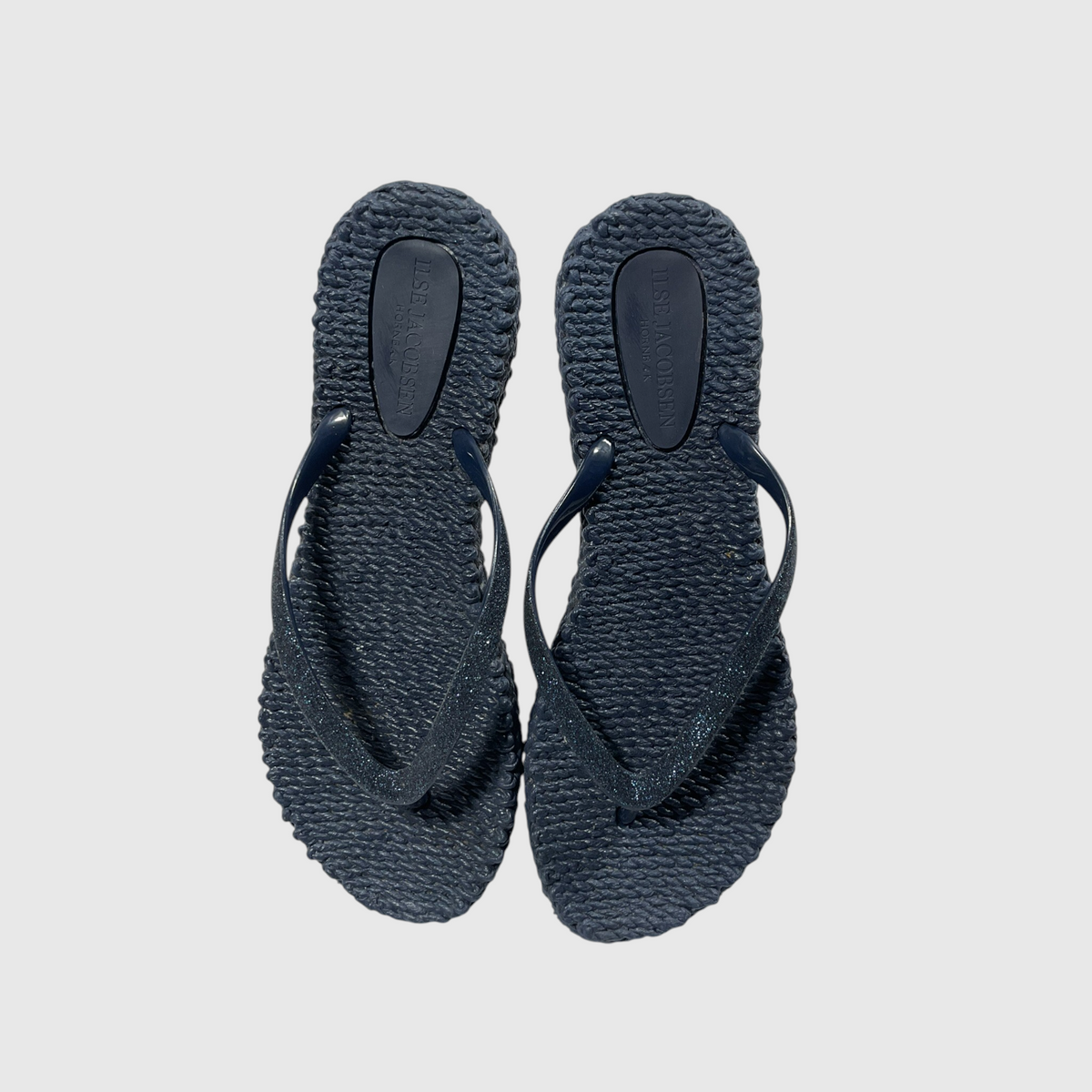 A pair of textured navy blue flip flops on a light gray background.