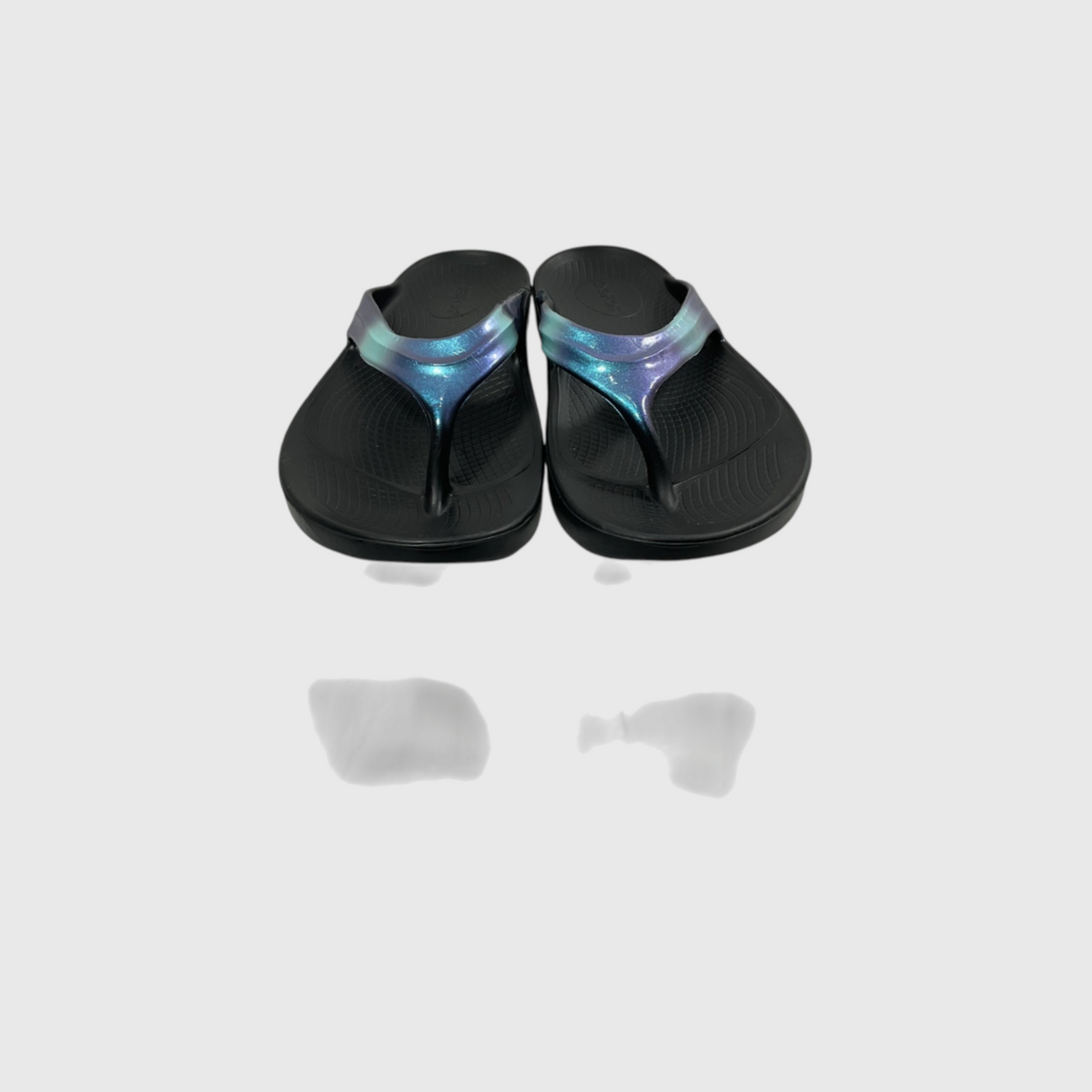 A pair of black flip-flop sandals with iridescent blue and purple straps, shown from a top-down view on a light gray background with a soft reflection below.