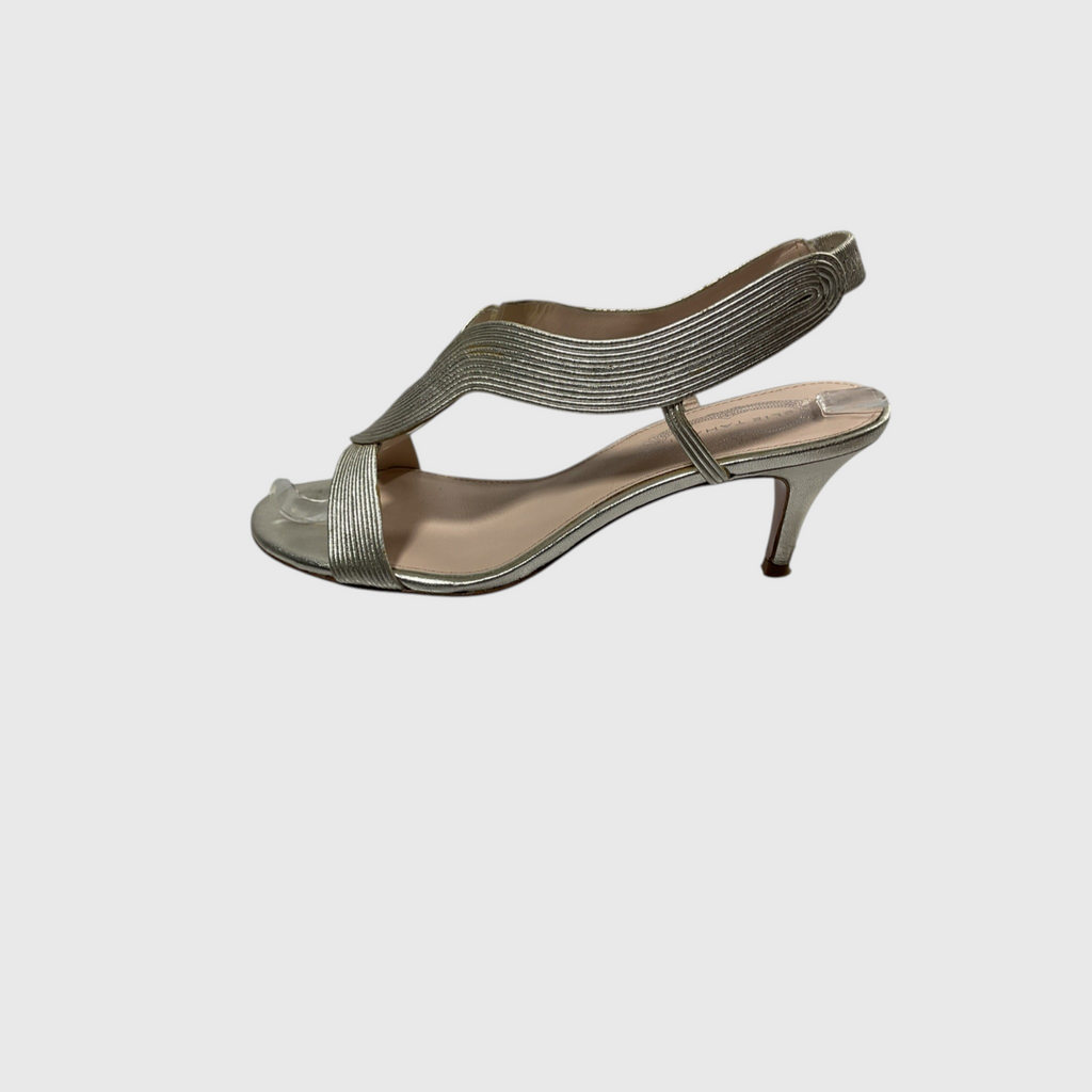 A metallic silver heeled sandal with a crisscross ankle strap and a low kitten heel, shown from a side profile on a light gray background.