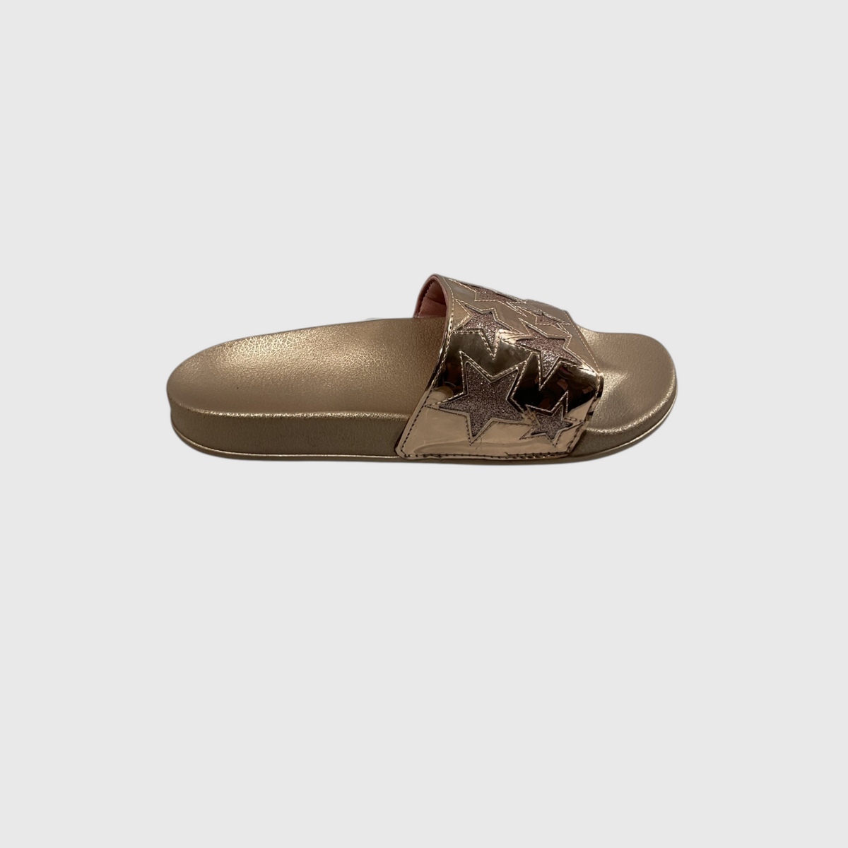 A metallic rose gold slide sandal with a strap featuring layered star cutouts, shown from a side profile on a light gray background.