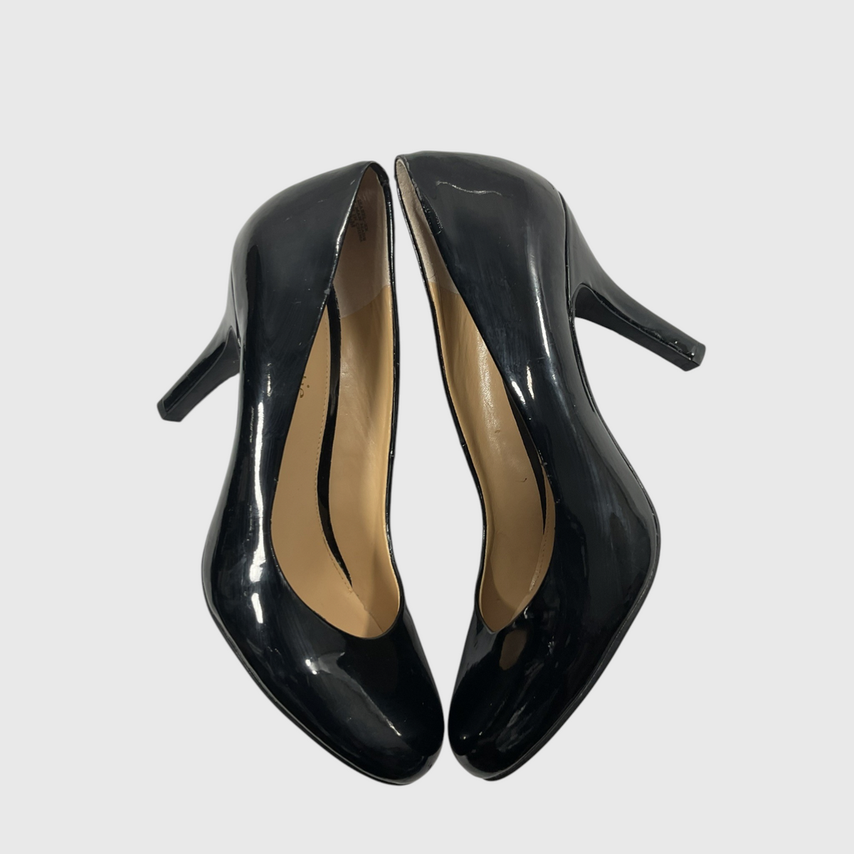A pair of glossy black patent leather high-heeled pumps with beige insoles, shown against a plain light gray background.